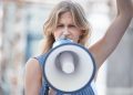 Protest, angry and woman talking with megaphone at a riot in the city of Iran. Face portrait of you.