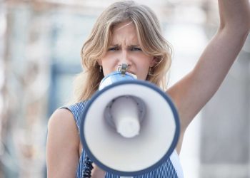 Protest, angry and woman talking with megaphone at a riot in the city of Iran. Face portrait of you.