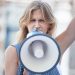 Protest, angry and woman talking with megaphone at a riot in the city of Iran. Face portrait of you.